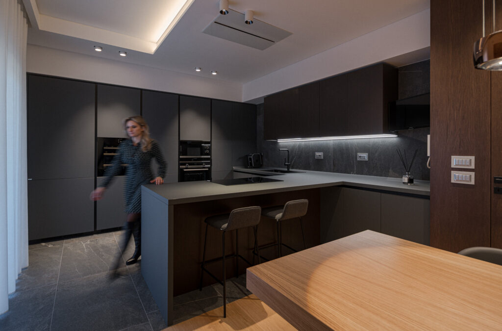 Cucina nera con penisola, sgabelli e figura in movimento