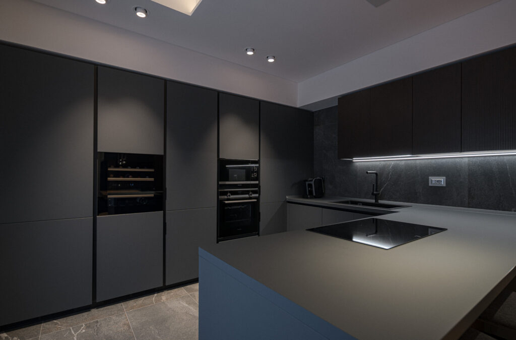 Cucina nera con colonne attrezzate, piano di lavoro e penisola