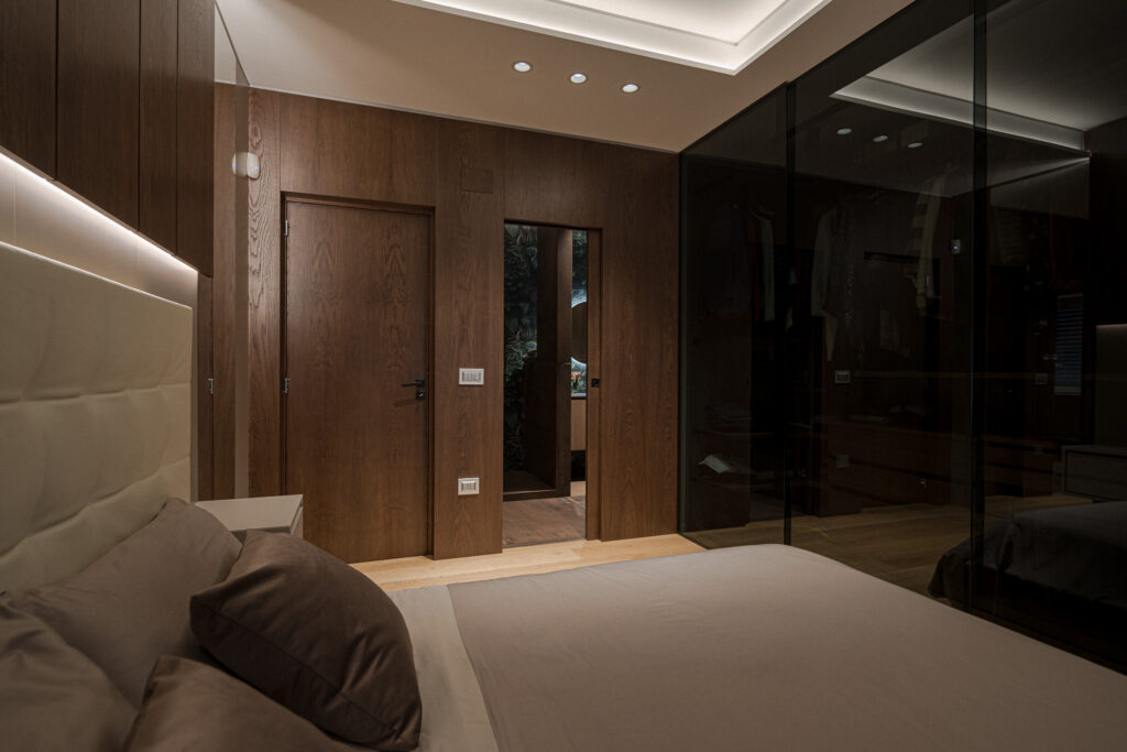 Letto in primo piano, pareti in legno e guardaroba vetrato