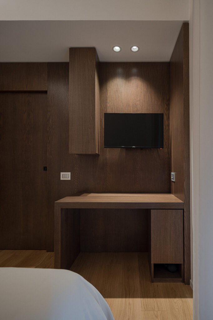 Scrivania in legno con televisore a parete e pensile verticale