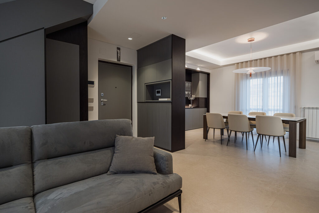 Soggiorno con divano grigio, ingresso e sala da pranzo