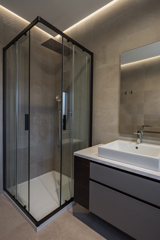 Box doccia con profili neri accanto al lavabo rettangolare