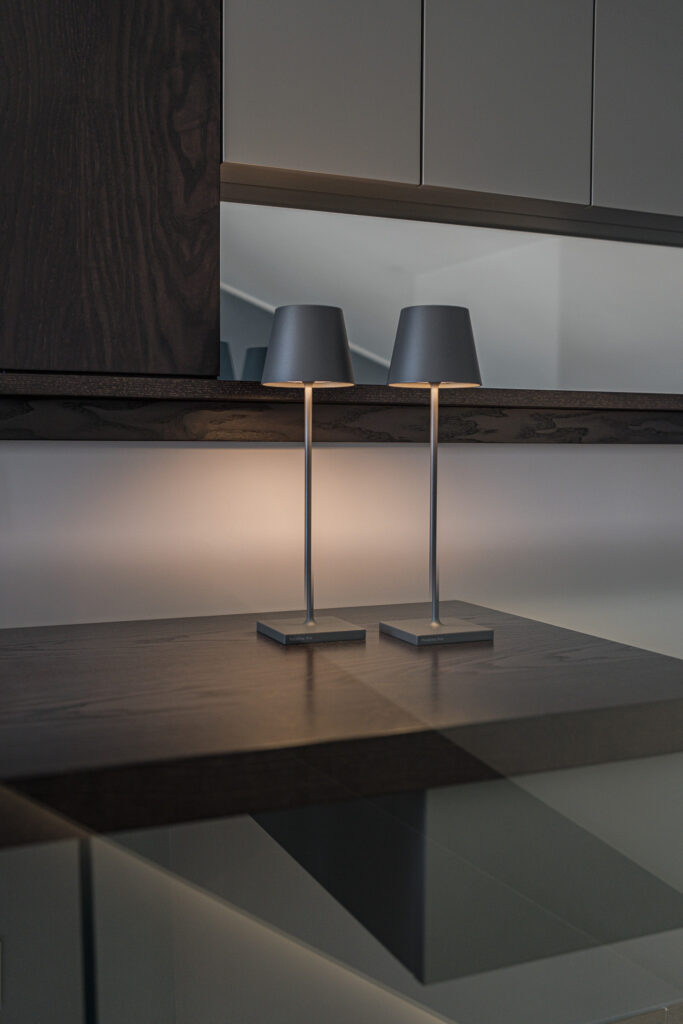 Due lampade nere accese sul piano in legno davanti allo specchio