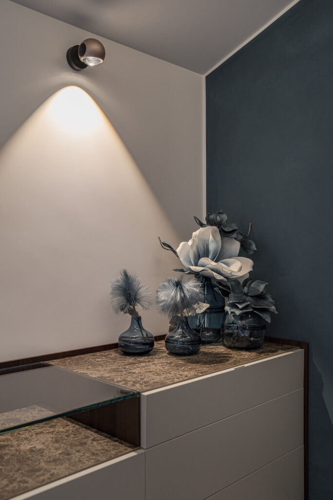 Cassettiera chiara con piano materico, vasi e fiori decorativi