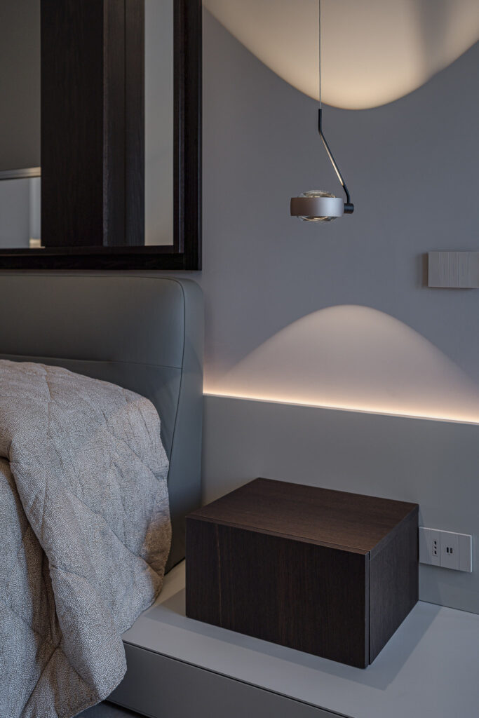 Comodino in legno su zoccolo grigio con lampada da lettura