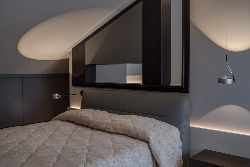 Letto matrimoniale con testiera grigia e grande specchio incorniciato