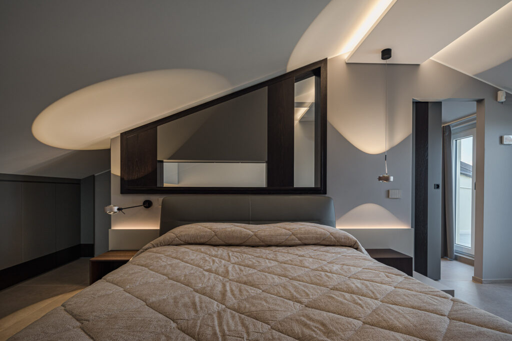 Letto matrimoniale con grande specchio e illuminazione radente sul soffitto
