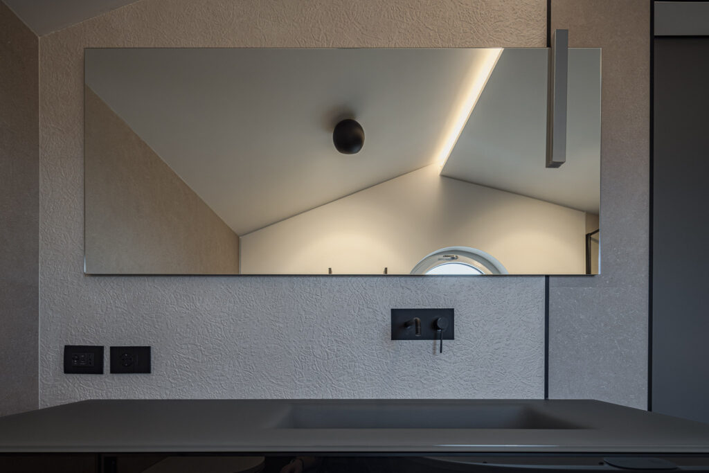 Grande specchio rettangolare sopra lavabo grigio con rubinetteria nera