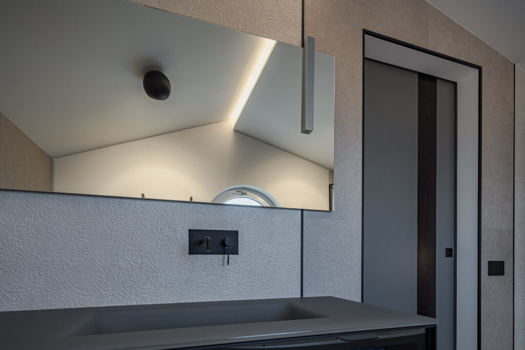 Lavabo grigio sotto grande specchio e porta scorrevole bicolore