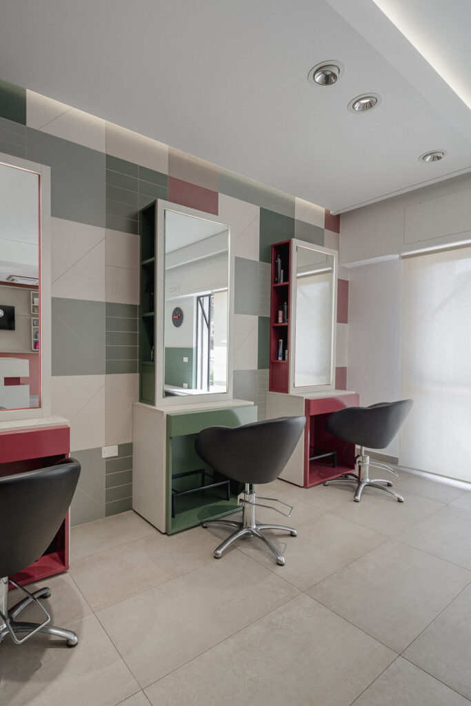 Specchi verticali con mobili rosa e verde e poltrone nere