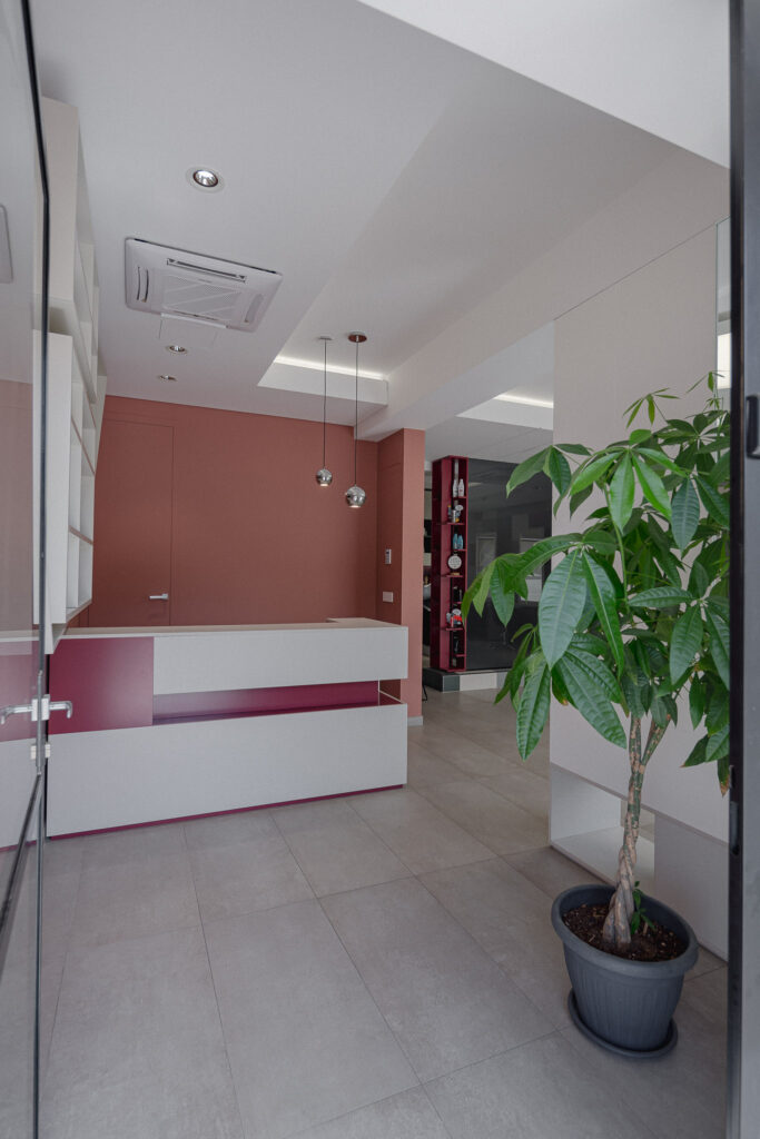 Ingresso del salone con pianta verde e banco reception bianco e rosa