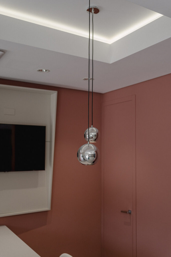Due lampade sferiche cromate davanti alla parete rosa del salone