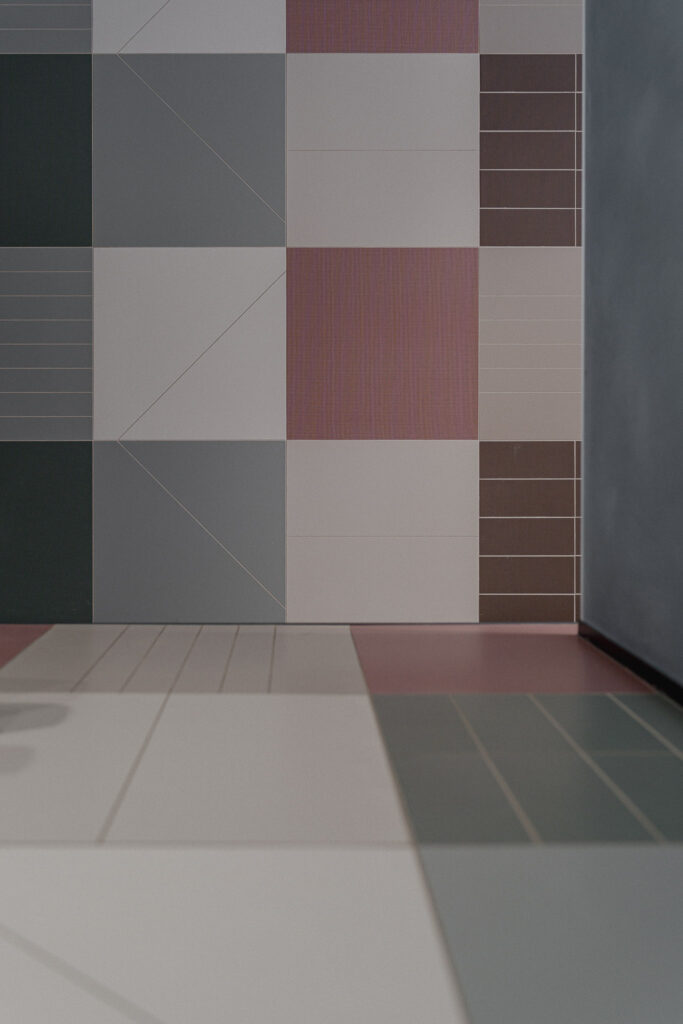 Rivestimento geometrico colorato che prosegue sul pavimento del salone