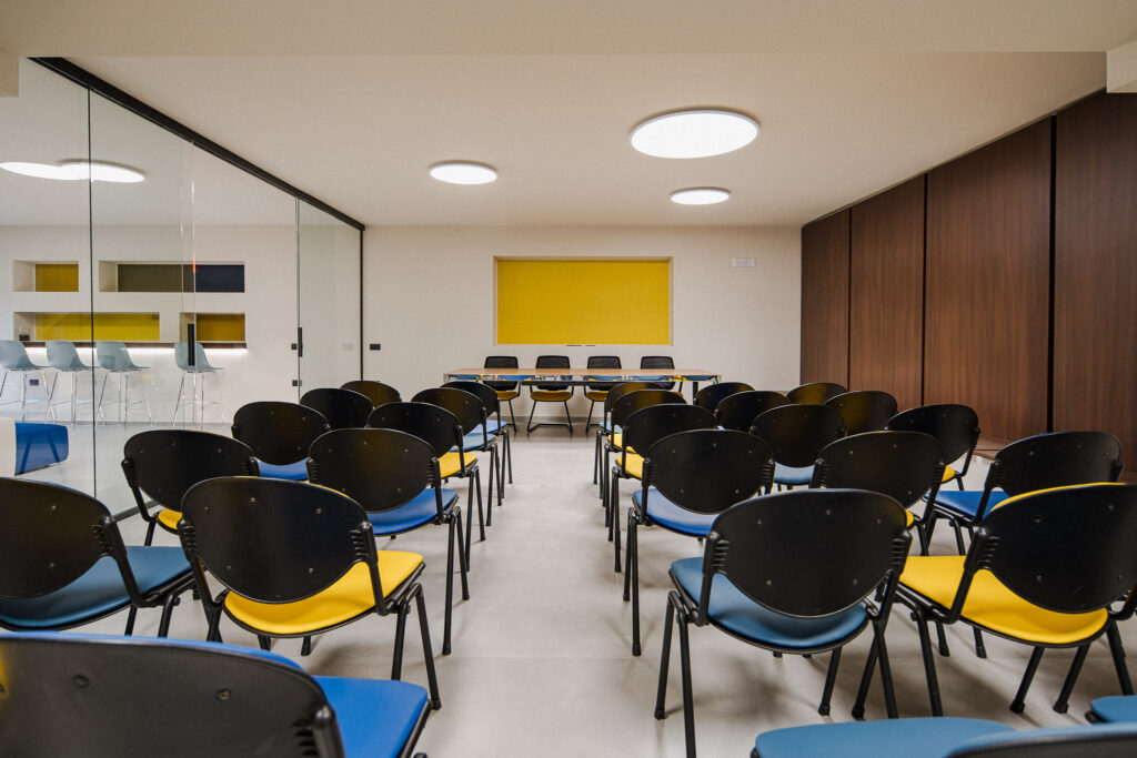 Sala conferenze con file di sedie e tavolo per i relatori