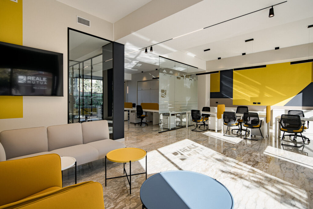 Lounge Reale Mutua con arredi colorati e pareti vetrate nere