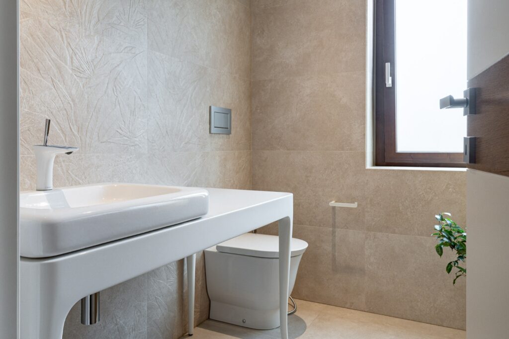 Bagno con lavabo bianco, sanitari e rivestimenti beige