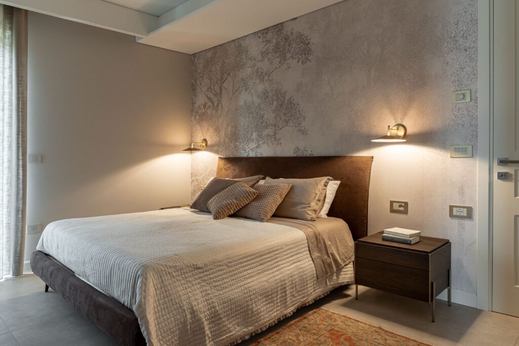 Letto matrimoniale con testiera marrone e parete decorata con alberi