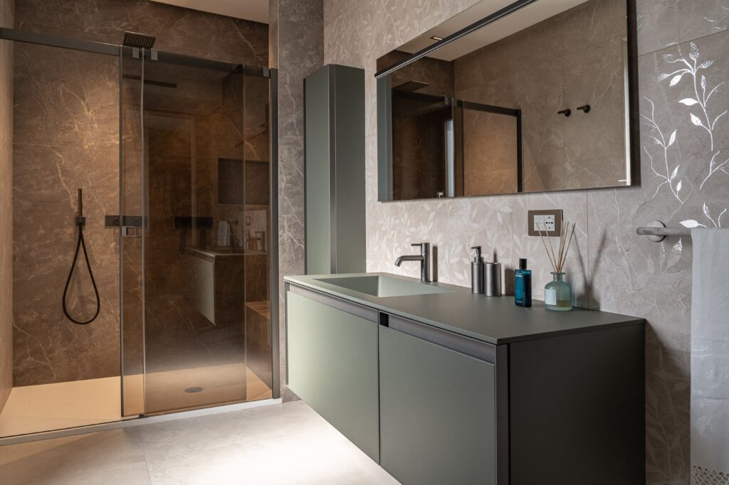 Mobile bagno verde salvia accanto a doccia con profili neri