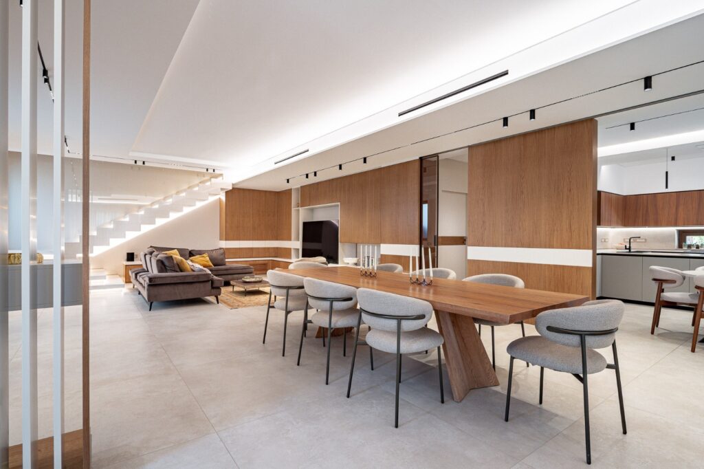 Sala da pranzo con tavolo in legno aperta sul soggiorno e sulla cucina