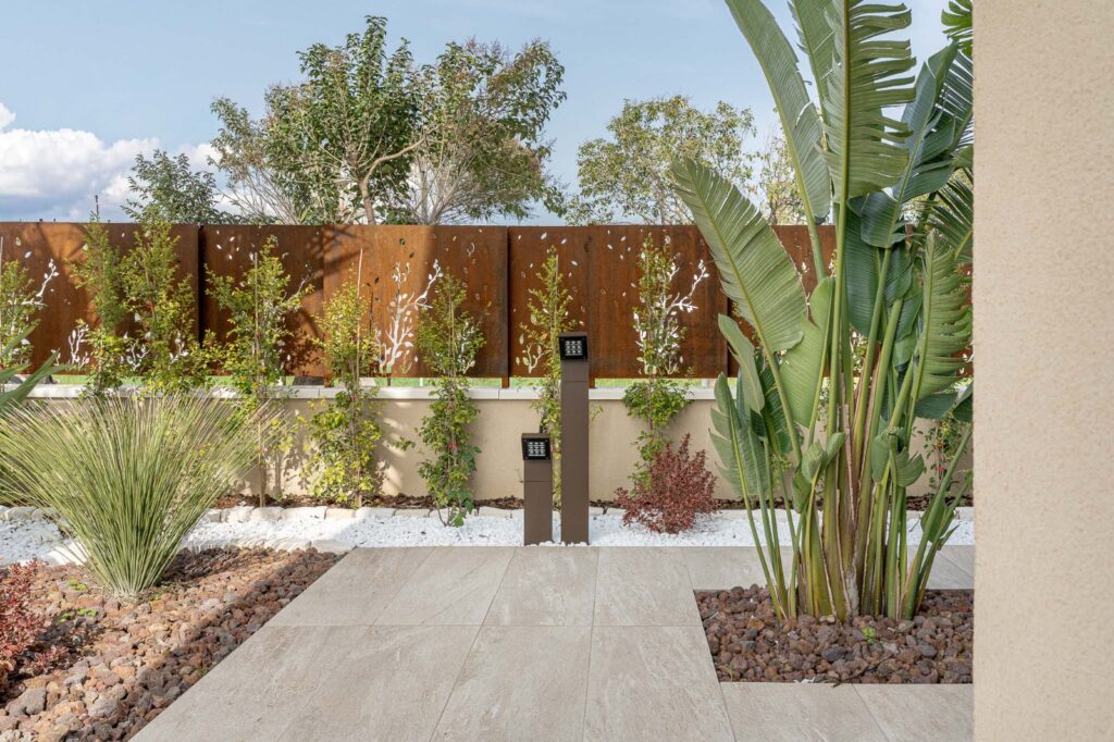 Camminamento tra aiuole mediterranee e pannelli decorativi in corten