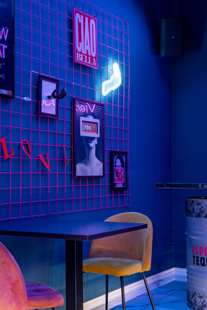 Griglia metallica con stampe, cornici e decorazioni luminose nel Drink Hub