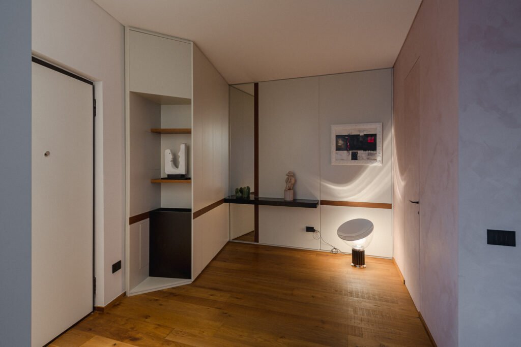 Ingresso dell’attico con armadiature su misura, parquet e illuminazione decorativa