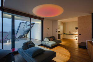 Living con divani modulari, vetrata sulla terrazza e proiezioni luminose colorate
