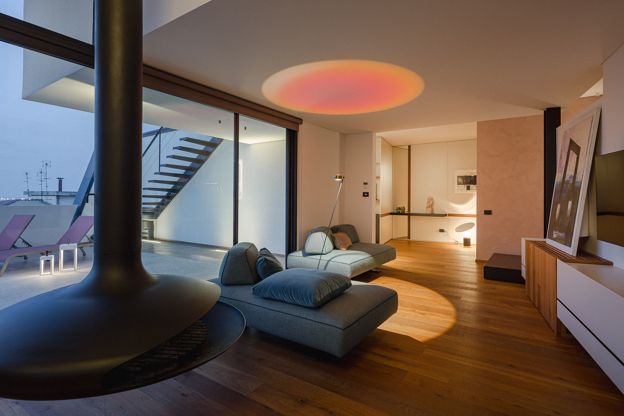 Living con camino sospeso nero, divani modulari e affaccio sulla terrazza
