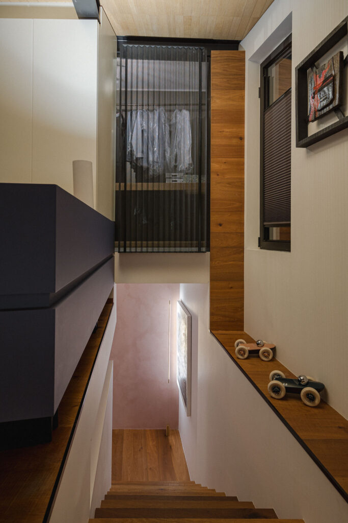 Scala interna in legno vista dall’alto con luce verticale e oggetti decorativi