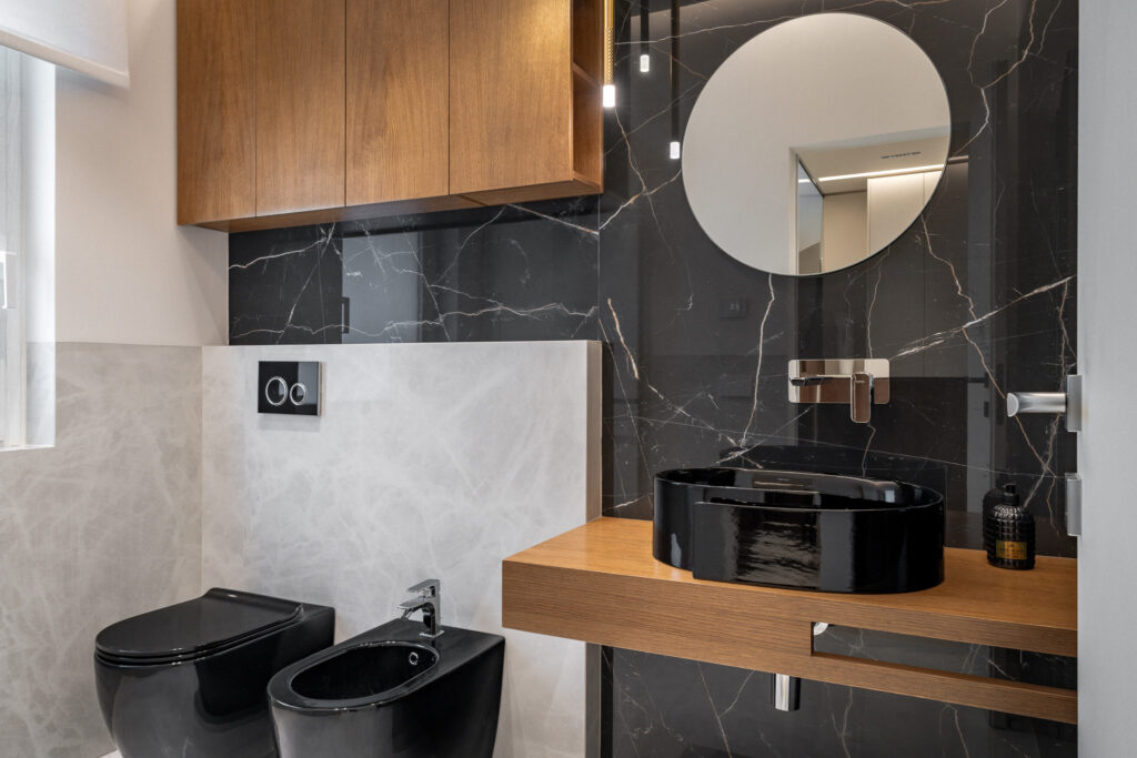 Bagno con sanitari neri, lavabo da appoggio e parete effetto marmo