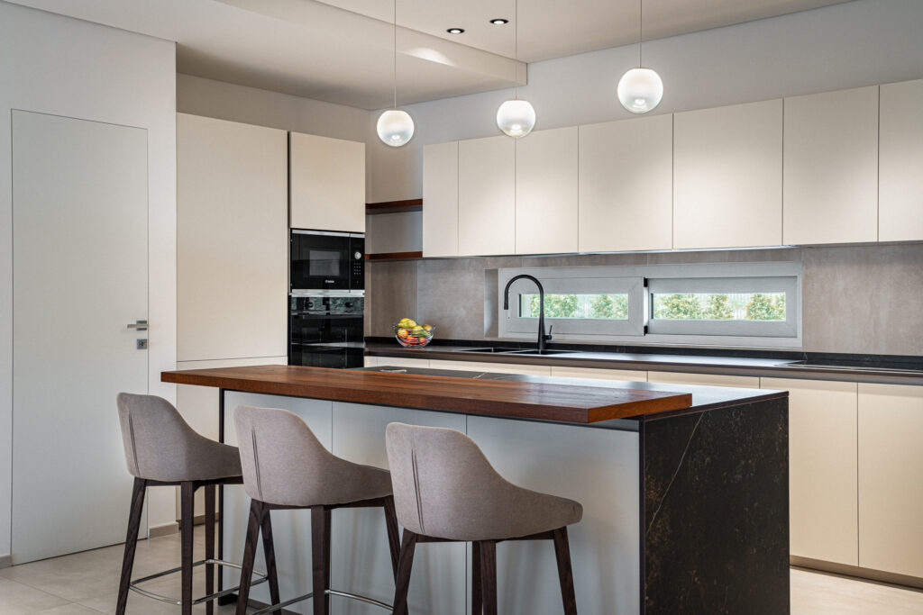 Cucina bianca con isola, piano snack in legno e lampade a sospensione