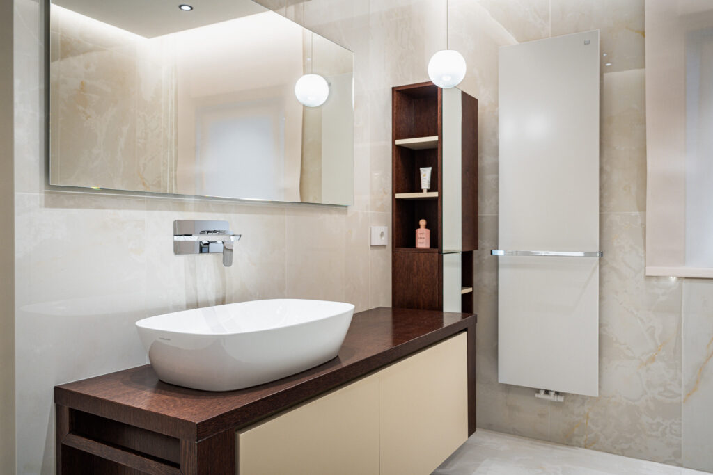 Bagno luminoso con lavabo da appoggio e mobile in legno e tonalità avorio