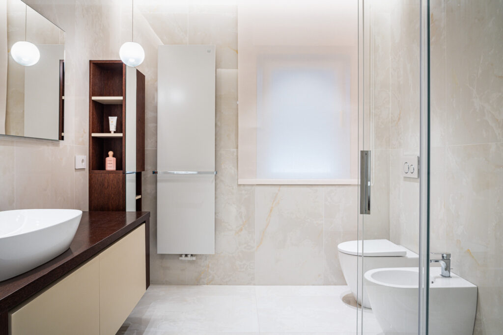 Bagno moderno con mobile lavabo, doccia in vetro e rivestimenti chiari