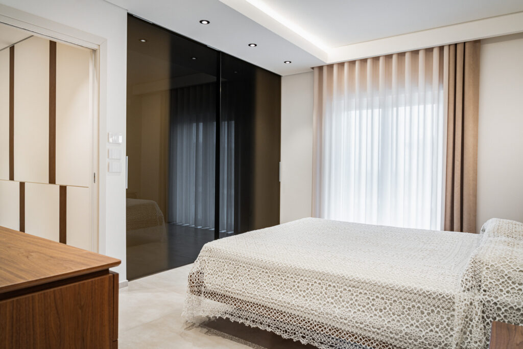 Camera da letto moderna con armadio in vetro fumé e tende a tutta altezza