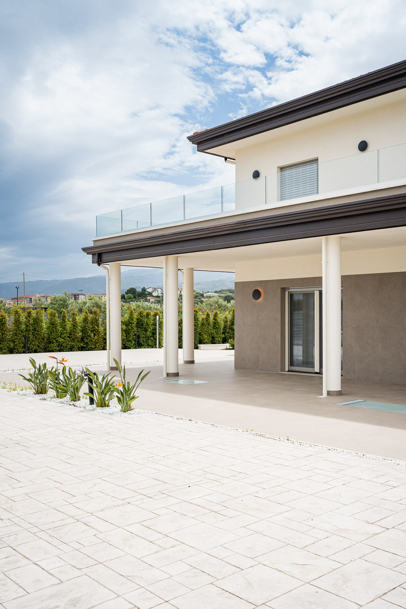 Esterno della villa con portico, terrazza in vetro e spazio pavimentato